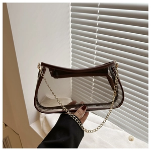 Detail of transparent PVC underarm bag with brown leather trim and golden metal chain