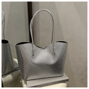 Detailed view of silver tote bag with woven texture and slender shoulder straps