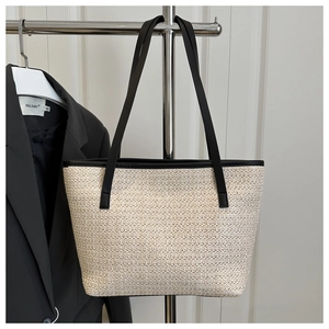 Close-up of the fine woven texture and black leather straps of the summer tote bag