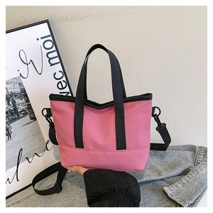 Detail of pink canvas tote bag with black straps on denim background in lifestyle setting