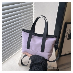 Détail d'un sac à main violet minimaliste en nylon avec des poignées noires et sangle