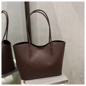 Detailed view of dark brown woven faux leather tote bag with fine geometric texture