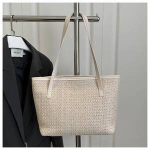 Macro detail of hand-woven straw tote bag in beige with slim shoulder straps and natural texture