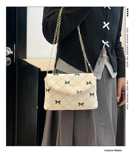 Chic beige corduroy crossbody bag with bow embroidery and gold chain strap shown on model