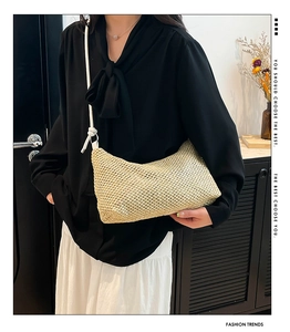 Detailed close-up of woven straw bag texture and white rope strap on female shoulder