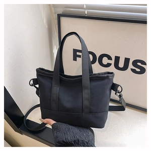 Close-up of black nylon tote bag with dual handles and adjustable shoulder strap detail