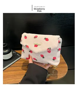 Detail view of cream strawberry print corduroy bag with gold chain and flap closure