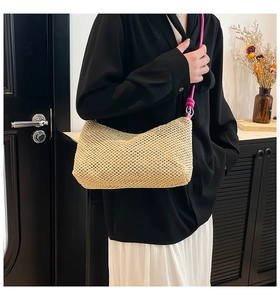 Detail of hand-woven straw tote with vibrant pink shoulder strap on a summer bag