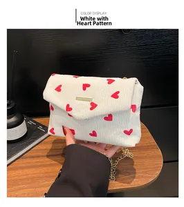 Detailed close-up of white corduroy heart pattern handbag with golden chain strap