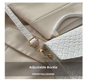 Detail of white woven texture handbag with golden adjustable buckle and strap