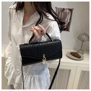 Detail of black woven pattern bag featuring a unique gold musical note twist lock