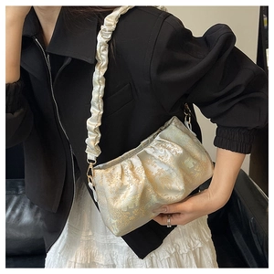 Detail of vintage-inspired pleated shoulder bag with gold patterns and scrunchie strap
