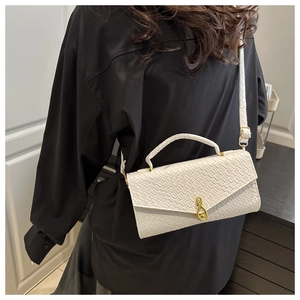 Crossbody view of white crocodile pattern square bag with gold music note lock