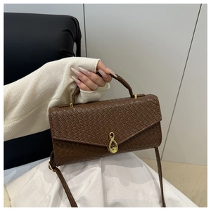 Detail of dark brown woven texture handbag with golden infinity twist lock closure