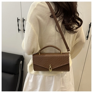 Detail of dark brown faux leather handbag with woven texture and gold figure-eight buckle
