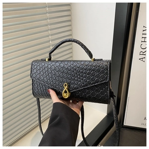 Detail of elegant black crocodile embossed crossbody bag with infinity golden metal clasp