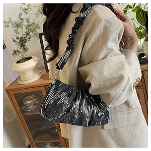 Detail of black sequined bucket bag with ruched shoulder strap and silver stripes