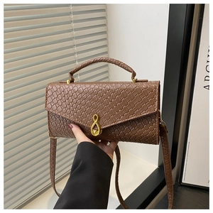 Close-up of brown woven texture PU leather handbag with golden infinity metal buckle