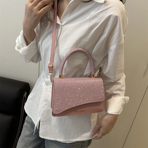 Pink glitter crossbody bag with top handle and miss.mini logo shown on model with jeans