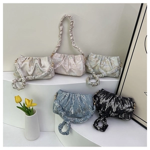 Detailed group shot of sequined pleated cloud bags in various colors on a display stand