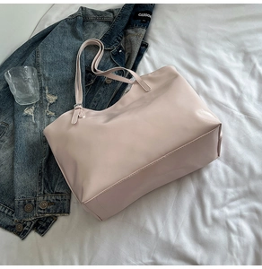 Top view of a large light pink tote bag made of smooth faux leather on a white cloth background
