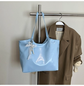 Detail of light blue patent leather tote bag with white lace and pearl bow charm