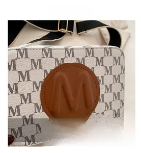 Close-up of camera bag featuring letter print patterns and brown leather logo patch