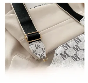 Close-up of adjustable woven shoulder strap with gold metal buckle on white monogram bag