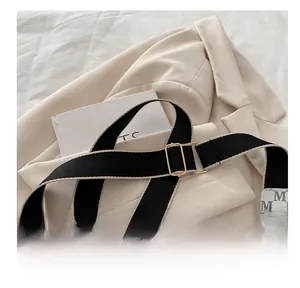 Detail of monogram print square bag with wide fabric strap and golden buckle