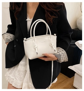 Détail du sac à main blanc en similicuir avec nœuds décoratifs et lettrage FASHION