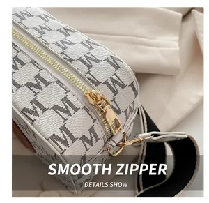 Détail du zip doré et du motif monogramme sur un sac photo élégant pour femmes