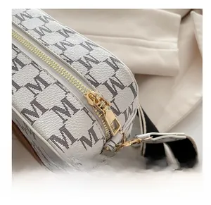 Detailed close-up of smooth gold zipper and monogram pattern on a fashion camera bag