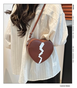 Detail of heart-shaped brown crossbody bag with lightning print and silver metal zipper