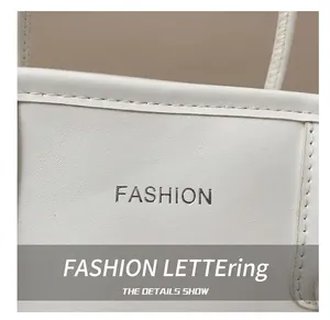 Dettaglio ravvicinato della borsa in pelle bianca con scritta fashion e cuciture rifinite