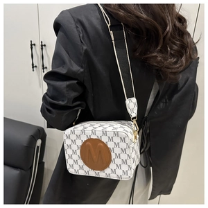 Vue détaillée du sac à bandoulière blanc avec motif M noir et large sangle contrastée