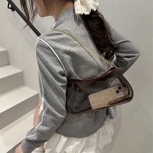 Sac à épaule transparent en PVC avec bordure marron et chaîne dorée porté par mannequin