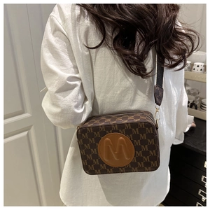 Détail du sac bandoulière vintage marron avec imprimé M et similicuir texturé