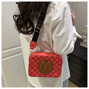 Vue détaillée d'un sac bandoulière rouge à motifs avec large sangle sur mannequin