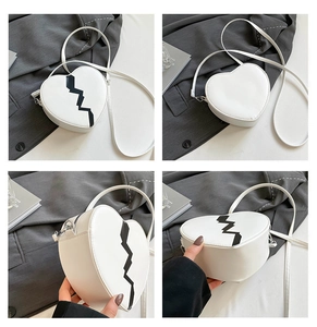 Detail view of heart-shaped crossbody bag featuring white leather and black lightning pattern