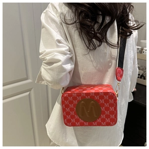 Détail du sac caméra rouge avec motif M blanc et large bandoulière en jacquard