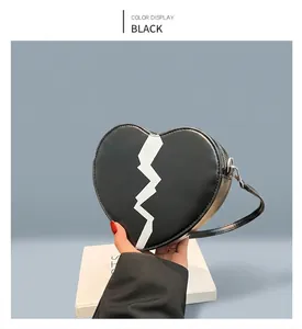 Detail of a black heart-shaped crossbody bag with white crackle pattern and silver zipper