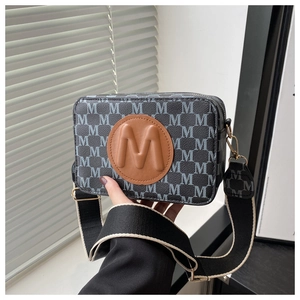 Détail du sac bandoulière carré imprimé avec patch logo cuir et sangle tissée