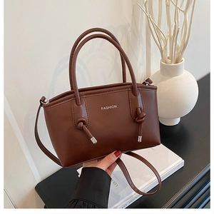 Détail d'un sac cabas marron foncé avec poignée nouée et inscription métallique tendance