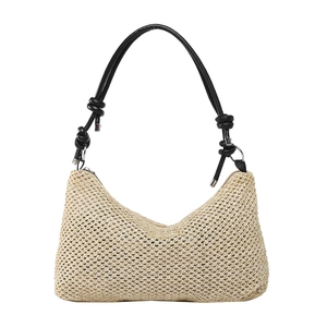 Handwoven straw tote bag with black leather knotted shoulder strap on white background
