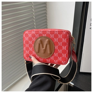 Détail d'un sac bandoulière rectangulaire rouge avec motif M blanc et sangle large