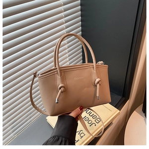 Détail du sac cabas beige en cuir avec poignées nouées et inscription FASHION élégante