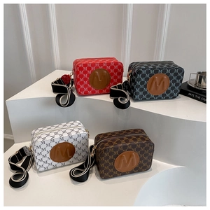 Détail de sacs bandoulière carrés avec imprimé M et bandoulière large à rayures bicolores