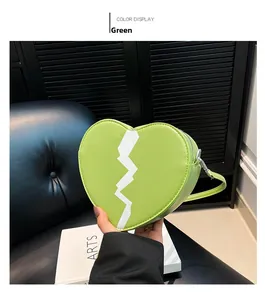 Detail of green heart-shaped crossbody bag with white broken heart pattern and silver zipper