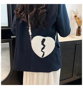 Modèle portant un sac bandoulière blanc en forme de cœur avec un motif de cœur brisé noir