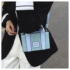 Close-up of a light blue mini tote bag with sparkling woven texture and a leather strap